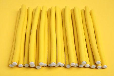 Curling rods on yellow background. hair styling toolの写真素材