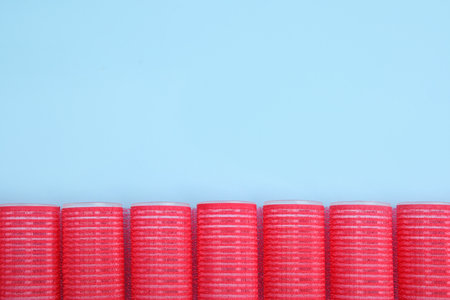 Hair curlers on turquoise background, flat lay. Space for textの写真素材