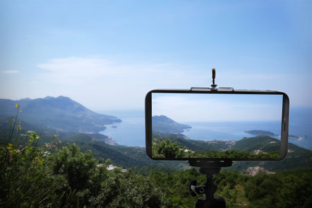 Taking photo of beautiful mountain landscape with smartphone mounted on tripod