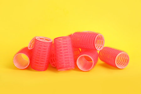 Many red hair curlers on yellow backgroundの写真素材