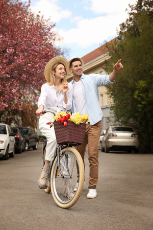 Lovely couple with bicycle and flowers on city streetの写真素材