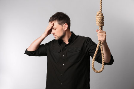 Depressed man with rope noose on light backgroundの写真素材