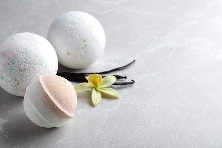 Fragrant bath bombs, vanilla sticks and flower on light gray table. Space for textの写真素材