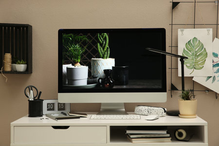 Stylish workplace with computer on white desk near beige wall. interior designの写真素材