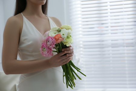 Bride with beautiful ranunculus bouquet indoors, closeup. Space for textの写真素材