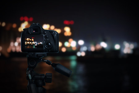 Taking photo of beautiful cityscape at night with camera mounted on tripodの写真素材