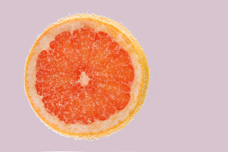 Slice of grapefruit in sparkling water on light background. Citrus sodaの写真素材
