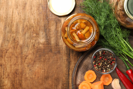 Delicious marinated mushrooms in glass jar on wooden table, flat lay. Space for textの写真素材