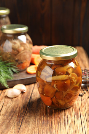 Delicious marinated mushrooms in glass jar on wooden tableの写真素材