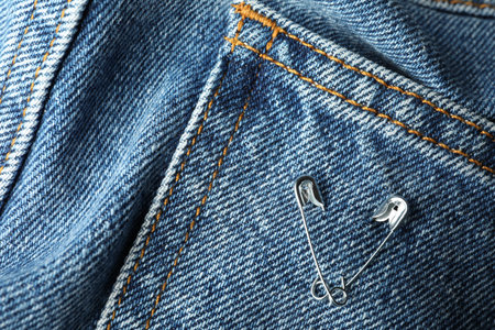 Metal safety pins on denim fabric, closeupの写真素材