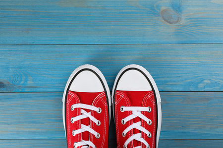 Pair of red sneakers on light blue wooden table, flat lay. Space for textの写真素材