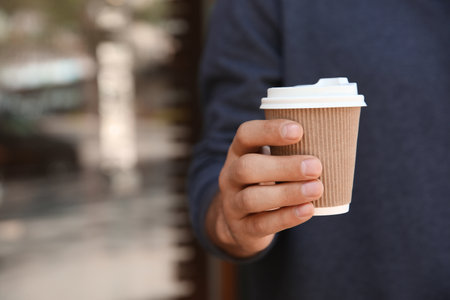 Man with takeaway coffee cup outdoors, closeupの写真素材