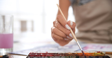 Young woman drawing with watercolors at table indoors, closeup. banner designの写真素材