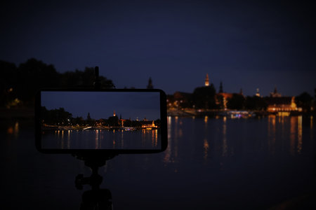 Taking photo of beautiful cityscape at night with smartphone mounted on tripodの写真素材