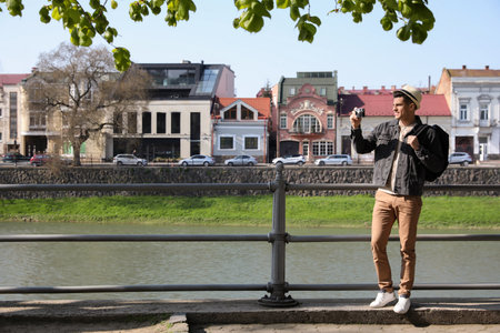 Tourist taking picture on city street near beautiful river