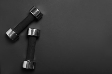 Dumbbells on black background, flat lay. Space for textの写真素材