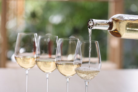 Pouring white wine from bottle into glass on blurred backgroundの写真素材