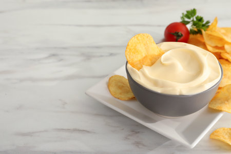 Potato chips and mayonnaise on white marble table, space for textの写真素材