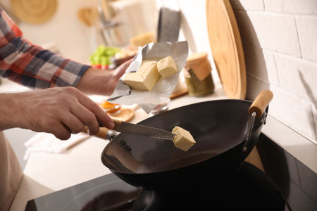 Man putting butter into frying pan, closeupの写真素材