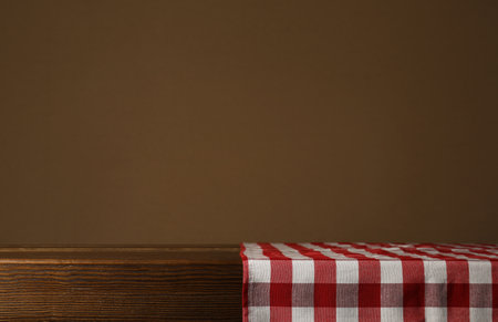 Red checkered textile napkin on wooden table. Space for text
