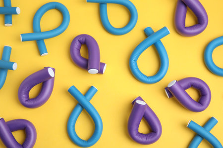 Curling rods on yellow background, flat lay. hair styling toolの写真素材