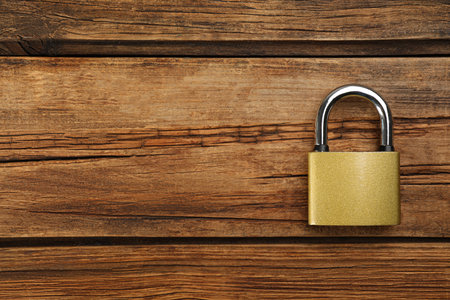 Modern padlock on wooden table, top view. Space for textの写真素材
