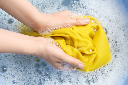 Top view of woman hand washing color clothing in suds, closeupの写真素材