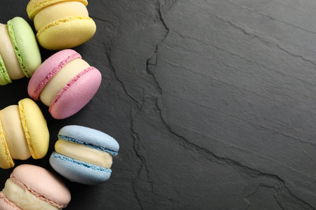 Delicious colorful macarons on black table, flat lay. Space for textの写真素材