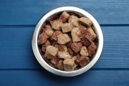 Wet pet food in feeding bowl on blue wooden table, top viewの写真素材