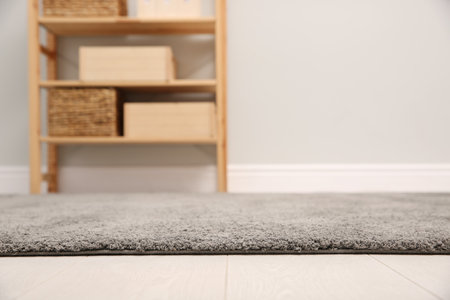 Room with shelving rack and light wall, focus on soft gray carpet. Space for textの写真素材