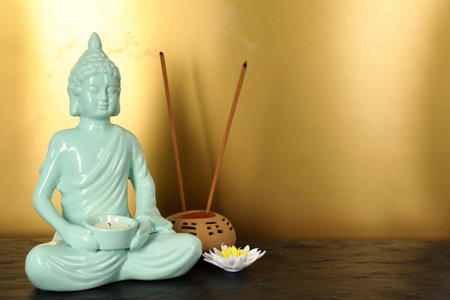 Buddha statue with burning candle near lotus flower and incense sticks on black table. Space for textの写真素材
