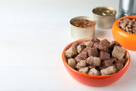 Wet pet food in feeding bowl on white wooden table. Space for textの写真素材