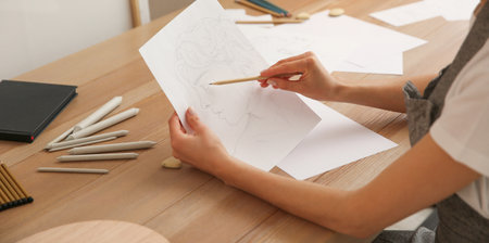 Young woman drawing male portrait at table indoors, closeup. banner design
