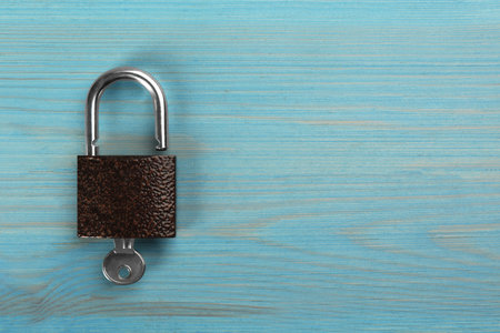 Modern padlock with key on light blue wooden table, top view. Space for textの写真素材