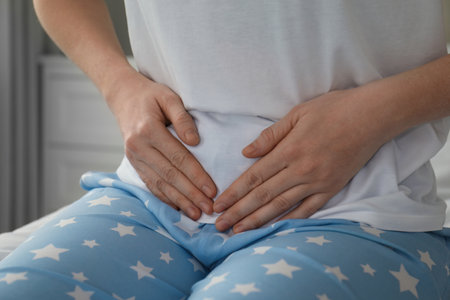 Woman suffering from abdominal pain at home, closeupの写真素材
