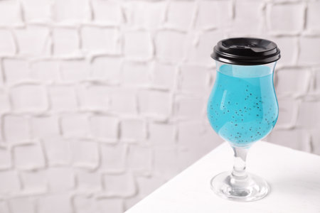 Light blue drink in glass with lid on white table, space for textの写真素材