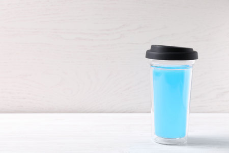 Bright light blue drink in glass with lid on white wooden table, space for textの写真素材