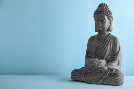 Beautiful stone Buddha sculpture on light blue background. Space for textの写真素材