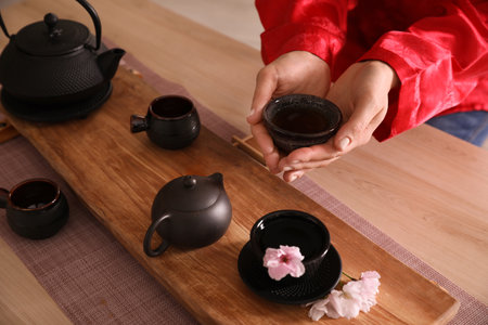 Guest holding cup of freshly brewed beverage during traditional tea ceremony at table, closeupの写真素材