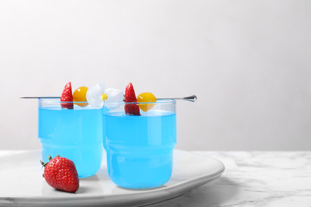 Bright light blue cocktail in glasses on white marble table, space for textの写真素材