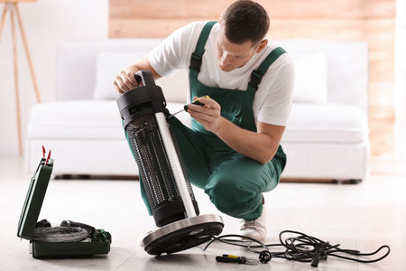 Professional technician repairing electric patio heater with screwdriver indoorsの写真素材