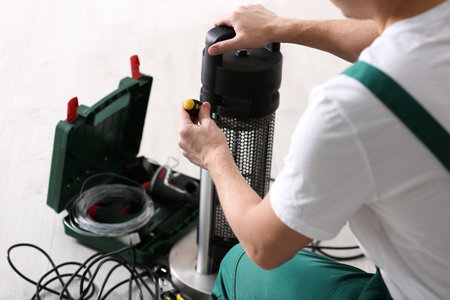 Professional technician repairing electric patio heater with screwdriver indoors, closeupの写真素材