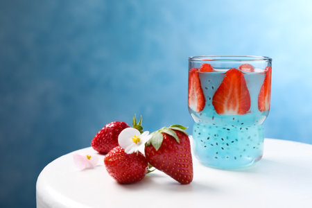 Light blue cocktail with strawberry and basil seeds on white table, space for textの写真素材