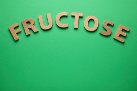 Word Fructose made of wooden letters on green background, flat lay. Space for textの写真素材