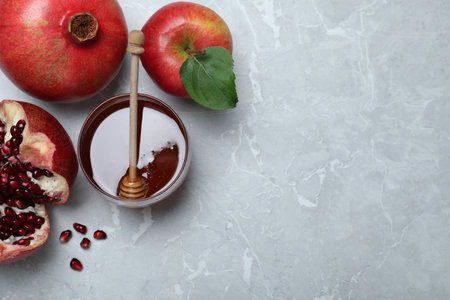 Honey, pomegranate and apples on gray marble table, flat lay with space for text. Rosh Hashanah holidayの写真素材