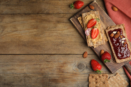 Fresh rye crispbreads with different toppings on wooden table, flat lay. Space for textの写真素材