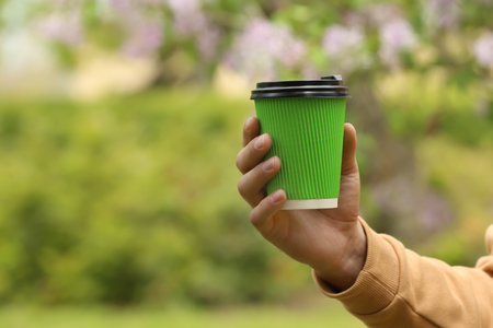 Man with takeaway coffee cup in park, closeup. Space for textの写真素材