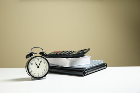 Alarm clock and office stationery on white table against beige background, space for text. time managementの写真素材
