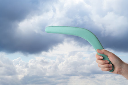 Woman holding boomerang against cloudy sky, closeupの写真素材