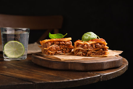 Delicious lasagna served on wooden table against black backgroundの写真素材